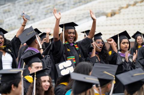 Graduates waive at camera.